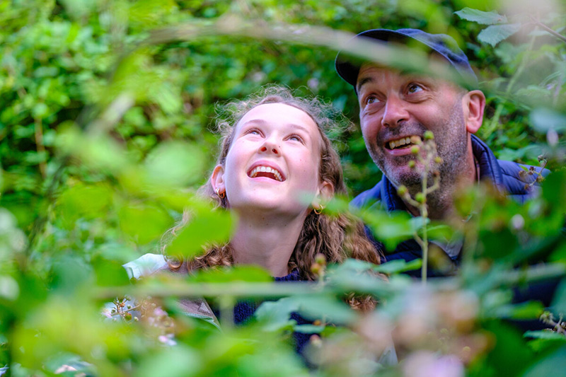 Father and daughter look at hedgerow plants